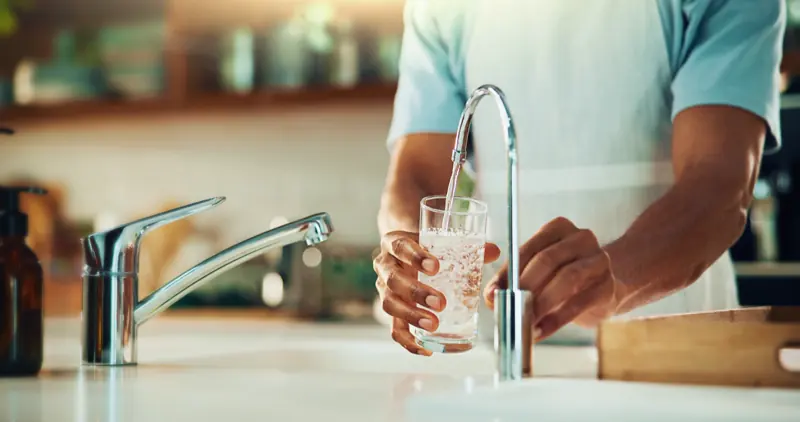 Clean water filling a glass from a kitchen faucet